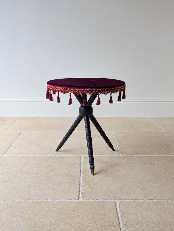 Antique Victorian ebonised gypsy table with a magenta velvet top, tasselled fringe, and spindle-turned tripod legs united by a central sphere.