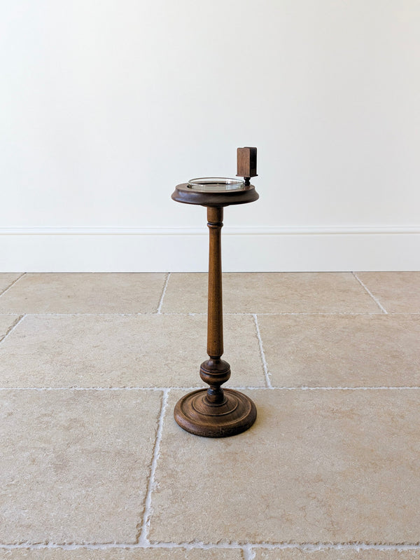 Antique Edwardian solid mahogany floor-standing smoker's stand featuring a dished gallery top with glass liner, matchbox sleeve, turned column, and stepped circular base.
