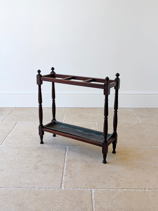 Antique Victorian mahogany stick stand featuring three upper compartments, turned finials, baluster uprights, an inset metal drip tray and turned feet.