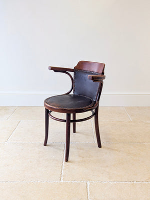 Antique Edwardian Thonet beech and leather desk armchair featuring a dark hide backrest and brass studding, raised on turned legs with a circular stretcher.