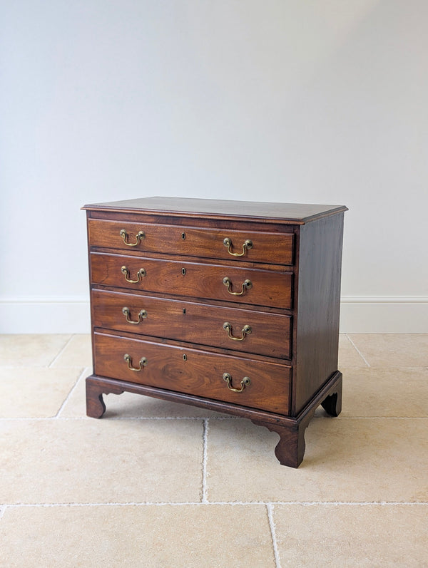 Antique George III mahogany chest of drawers with four graduated drawers and brass swan-neck handles, raised on shaped bracket feet.