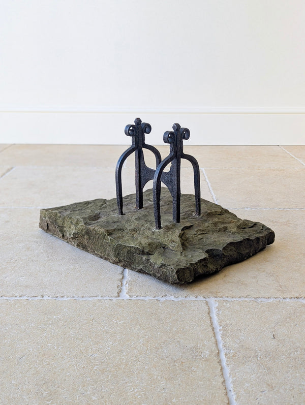 Antique Georgian hand-forged wrought iron boot scraper with arched end-frames and diamond finials, raised on lead-sealed sockets over a Yorkstone plinth.