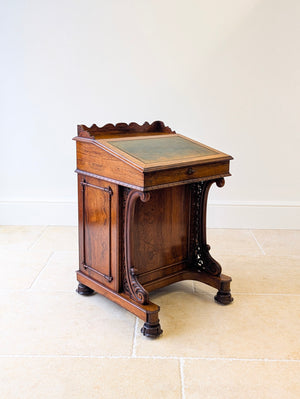 Antique William IV rosewood Davenport desk with a green leather sloped top which lifts open, carved lower supports and to one side a cupboard which opens to reveal a bank of drawers.