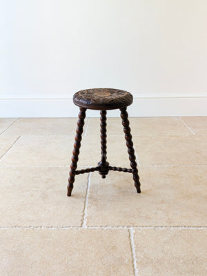 Antique late Victorian oak tripod stool featuring a carved sunflower top set over three splayed bobbin legs with a tripartite stretcher.