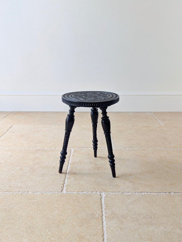 Antique Victorian ebonised hardwood occasional table featuring a deeply chip-carved circular top raised on three turned and carved threaded splayed legs.