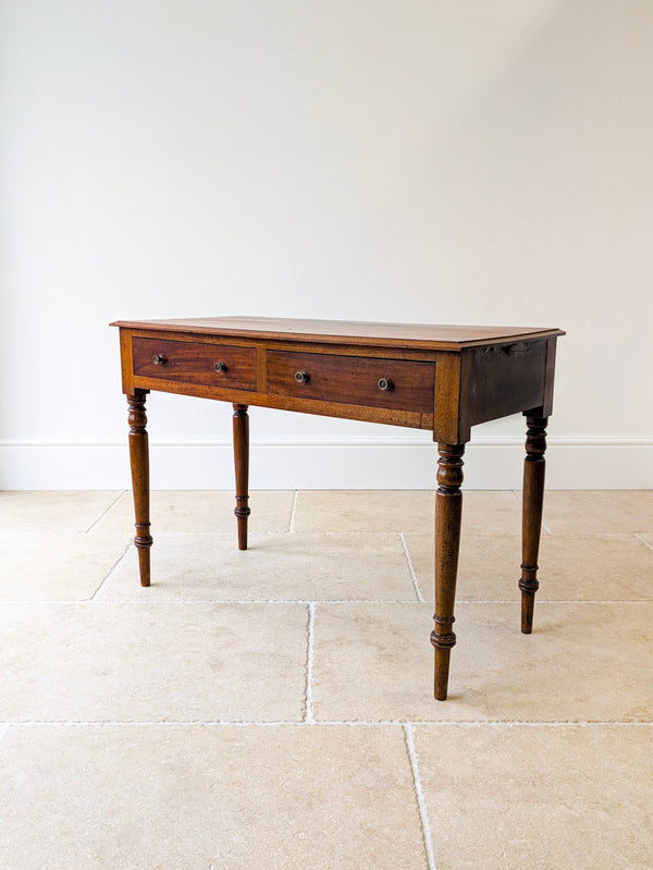 Antique Victorian mahogany writing table with a stepped moulded solid top, flush-fronted drawers with cast brass rosette handles, and ring-turned tapering legs.