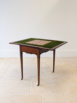 Antique Edwardian mahogany games table with a folding top, green baize playing surface, inlaid chessboard, drawers, and slender tapering square legs.