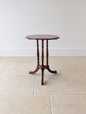 Antique Regency mahogany octagonal occasional table with a stepped edge top, three turned pillars, a triform platform, and down-swept legs.