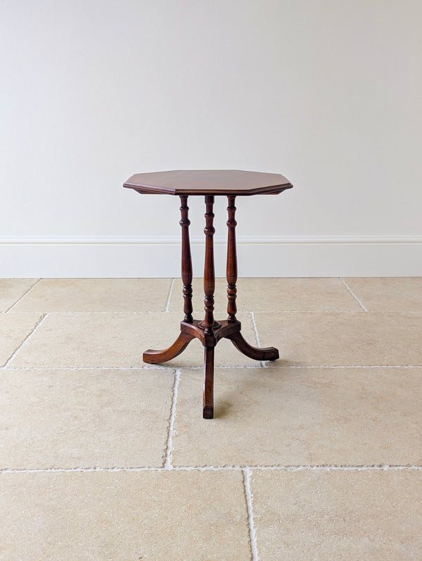 Antique Regency mahogany octagonal occasional table with a stepped edge top, three turned pillars, a triform platform, and down-swept legs.