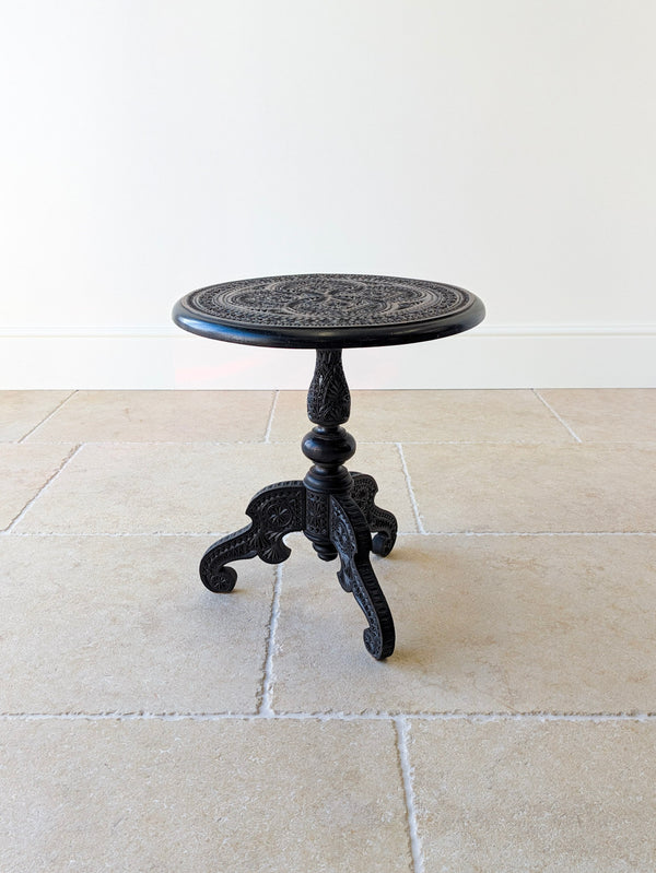 Antique Victorian Anglo-Indian ebonised hardwood occasional table with a carved circular top, turned baluster column, and carved tripod base on scroll feet.  