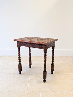 Antique fruitwood side table featuring a foliate and geometric carved top, continuous carved apron, and bobbin-turned legs with bun feet.