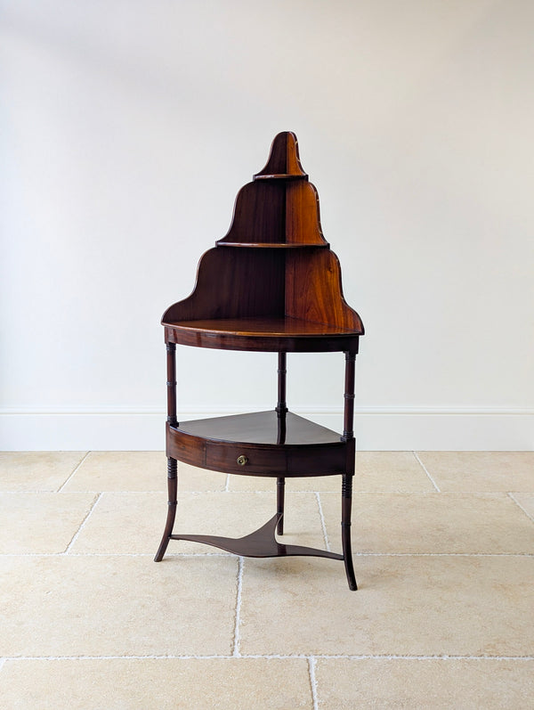 Antique Regency mahogany corner stand with a graduated superstructure, bow-fronted frieze drawer, ring-turned columns, and out-swept splayed legs.
