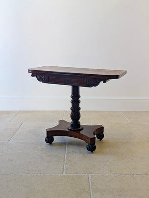 Antique William IV mahogany fold-over tea table featuring a boxwood-inlaid top, acanthus-carved pillar, and quadform platform base on gadrooned bun feet.