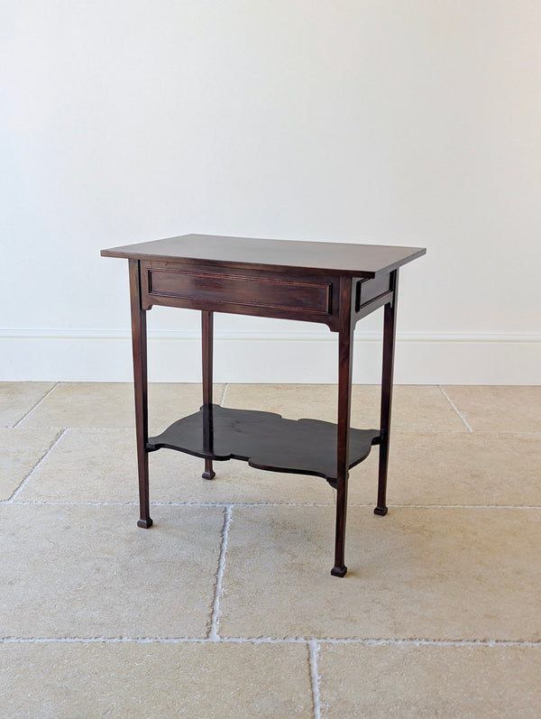Antique late Victorian mahogany side table with applied geometric panel mouldings, corner spandrels, a serpentine lower undertier, and flared block feet.