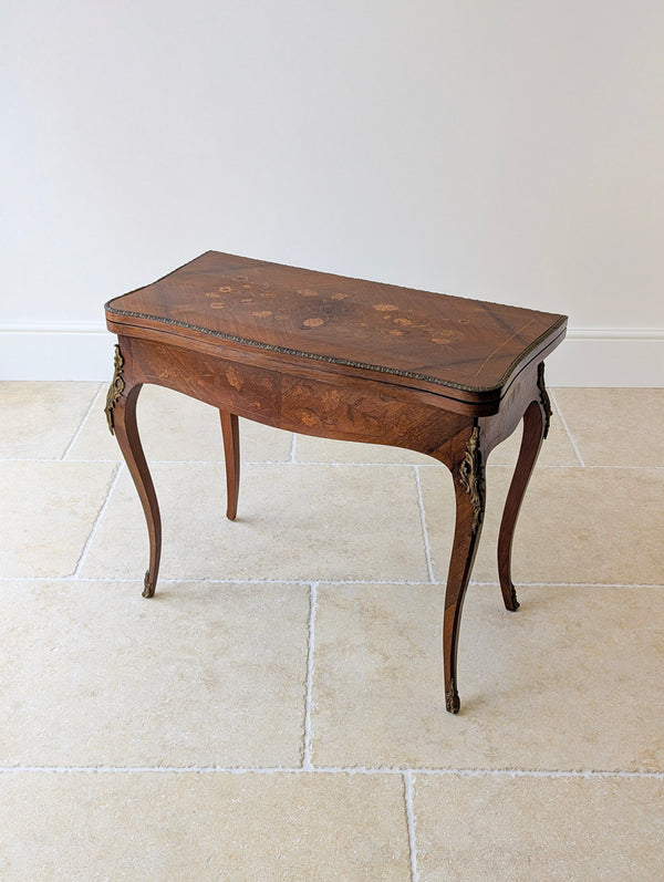 Antique late Victorian Louis XV style kingwood card table featuring floral marquetry, ormolu mounts, a serpentine frieze, and cabriole legs.
