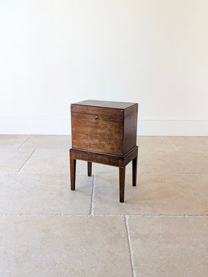 Antique George III mahogany cellaret featuring a hinged rectangular lid, an inlaid lozenge escutcheon, and boxwood stringing, raised on square tapered legs.
