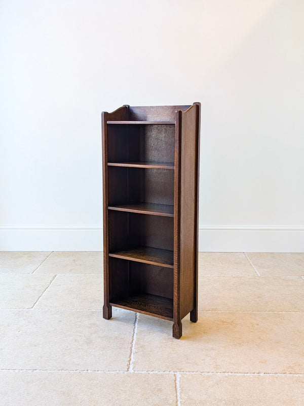 Antique Edwardian Arts & Crafts oak narrow open bookcase featuring a galleried tray top, four shelves, and chamfered uprights on square-cut feet. 