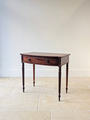 Regency mahogany bow-fronted side table with an ebonised geometric stringing drawer front raised on hand-carved reeded tapering legs and peg feet.