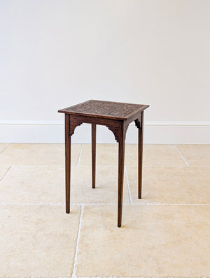Antique Edwardian Arts & Crafts oak occasional table featuring a carved foliate top, raised on slender square legs with shaped corner brackets.