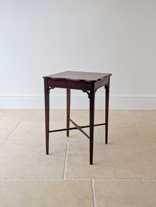 Antique Edwardian Chippendale Revival mahogany square occasional table featuring a wavy edge top with satinwood cross-banding on square legs with a sweeping X-form stretcher.