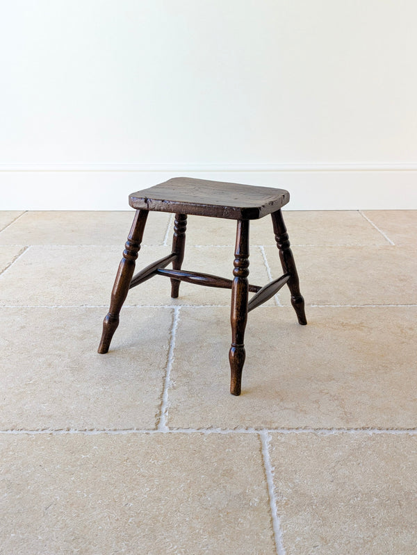 Antique Victorian English elm low country stool with a thick figured top, raised on splayed turned beech legs united by an ash H-stretcher.