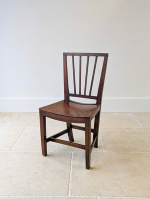Antique Victorian North Country vernacular solid oak side chair with slat back and curved seat raised on square legs and stretchers.