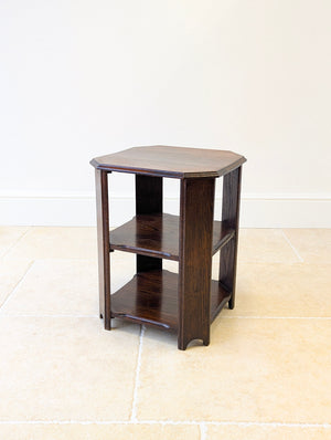 Antique Arts & Crafts style oak octagonal occasional table featuring a moulded edge top, two open shelf tiers, and four uprights with arched cut-out feet.