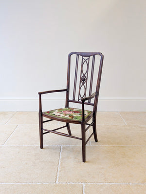 Antique Edwardian mahogany elbow chair with a tall openwork back centred by a carved rosette roundel, shaped arms, an upholstered seat, and line inlay.