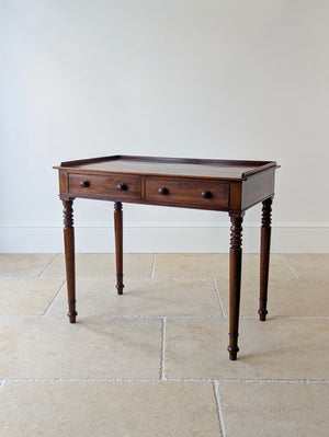 Antique William IV mahogany writing table featuring a low three-quarter gallery top over two drawers raised on ring-turned legs.