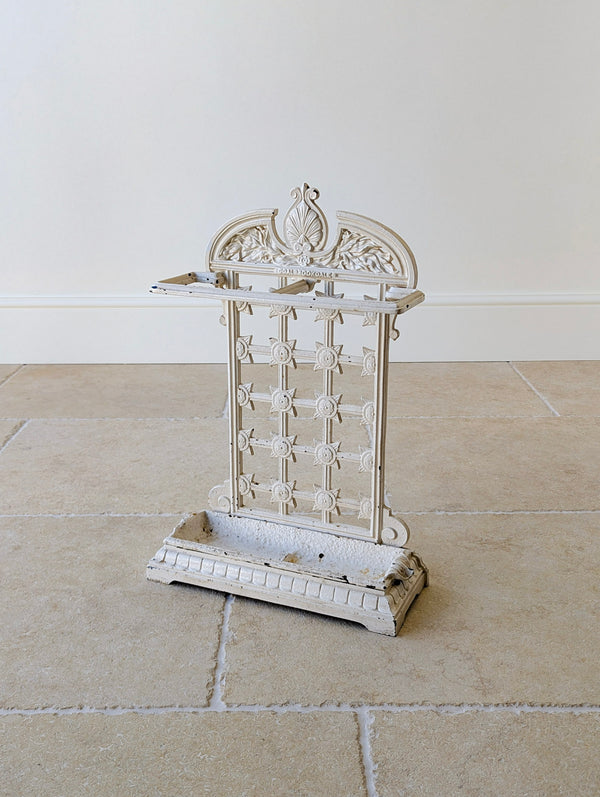 Antique late Victorian cast iron stick stand by Coalbrookdale with an arched Neoclassical cresting, openwork trellis back, and gadrooned plinth base with drip tray.