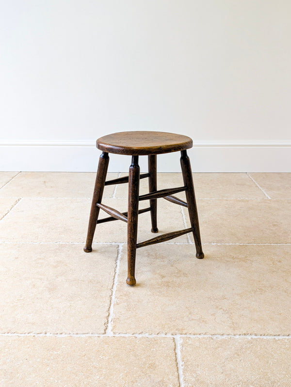 Antique late Victorian elm and beech country stool with a circular single-piece seat raised on splayed turned legs united by double-tier stretchers.  