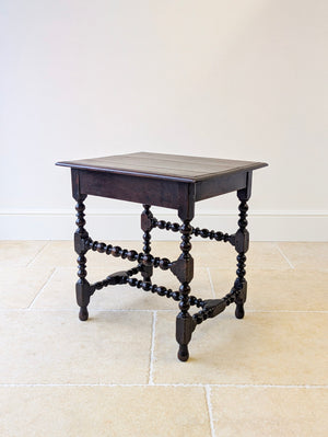 Antique Charles II oak side table featuring a moulded top over a deep frieze, raised on bobbin-turned legs with dual-tier stretchers and turned feet.