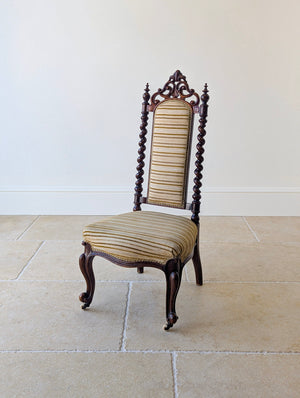 Antique Mid-Victorian walnut high-back parlour chair featuring a hand-carved C-scroll cresting rail, barley-twist stiles, and carved cabriole legs with white ceramic castors.