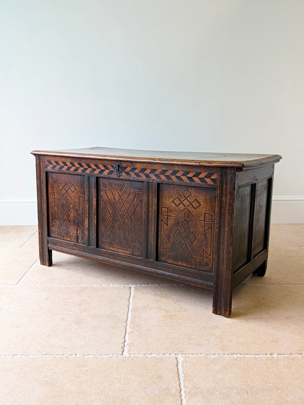 Antique Charles II West Yorkshire oak coffer with a bog oak and holly chevron frieze and geometric knotwork panels, raised on feet.