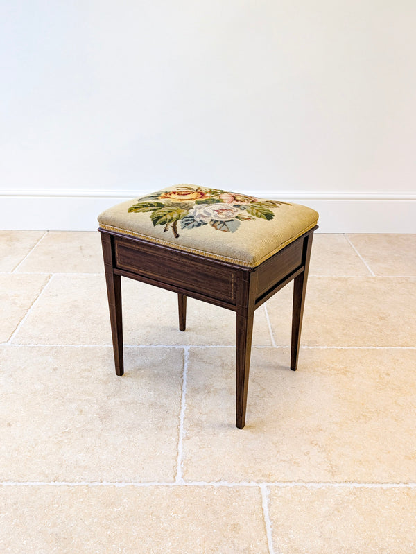 Antique Edwardian mahogany piano stool with a floral needlepoint seat opening to internal storage, framed in boxwood stringing, raised on tapering legs.