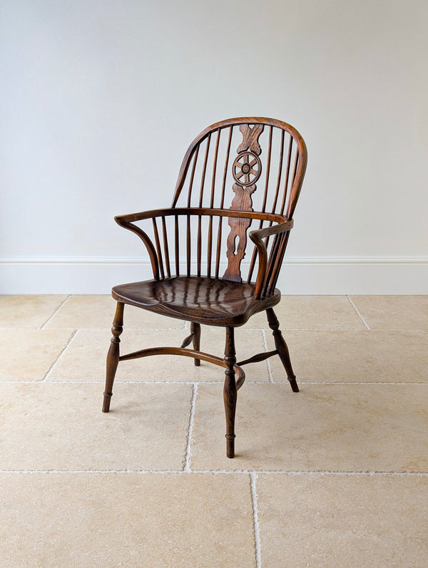 Antique George III ash and elm wheelback Windsor armchair with a hand-fretted splat, single-piece saddle seat, and hand-turned legs united by a crinoline stretcher.