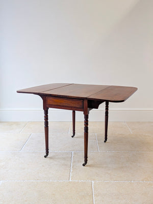 Regency mahogany Pembroke table with ebony and satinwood line inlay over a single frieze drawer raised on turned legs and brass cup castors.