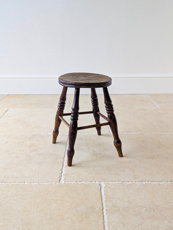 Antique Victorian country stool with circular elm seat and splayed ring-and-baluster turned beech legs.