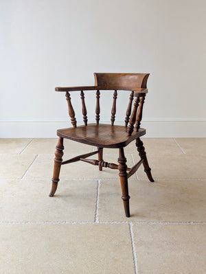 Antique Late Victorian elm and beech captain's desk chair with a shaped horseshoe arm rail, backrest block, contoured seat, baluster-turned legs, and turned H-stretcher.