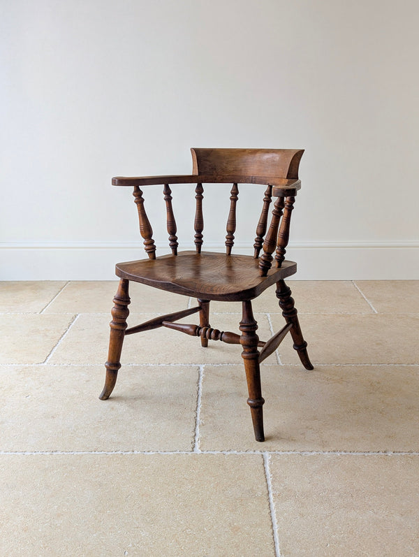 Antique Late Victorian elm and beech captain's desk chair with a shaped horseshoe arm rail, backrest block, contoured seat, baluster-turned legs, and turned H-stretcher.