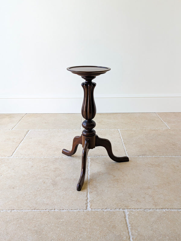 Antique Late Victorian mahogany tripod candle stand with a circular top, raised moulded border, fluted baluster stem, and sweeping cabriole legs on pad feet.
