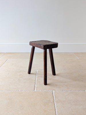 Antique Victorian oak jeweller's stool with a thick single-piece rough-sawn slab seat with exposed wedged through-tenons, raised on three hand-faceted splayed legs.