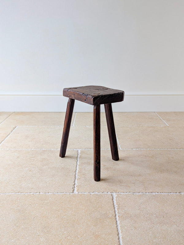Antique Victorian oak jeweller's stool with a thick single-piece rough-sawn slab seat with exposed wedged through-tenons, raised on three hand-faceted splayed legs.